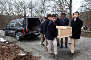 Teens carrying a casket from a hearse