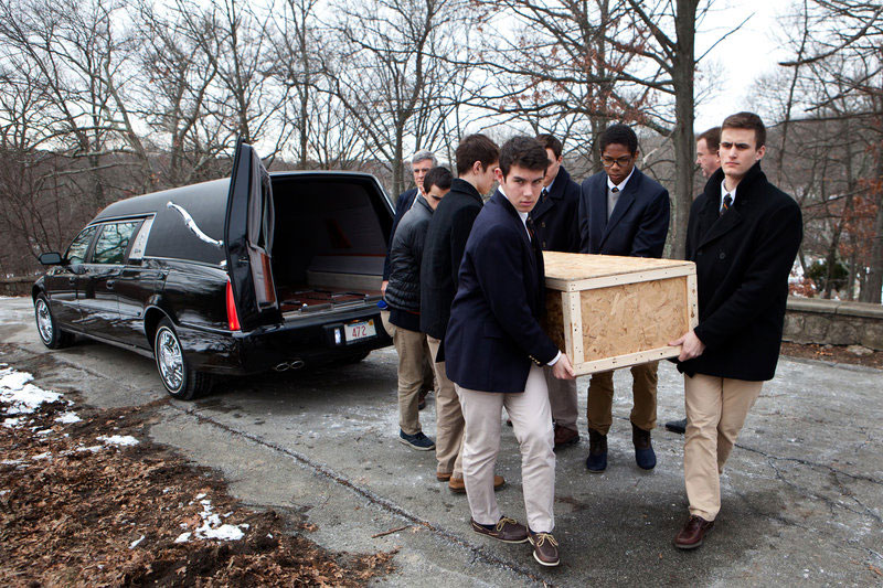 Teens carrying a casket from a hearse
